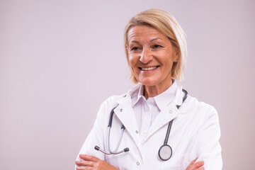 Portrait of mature female doctor on gray background.