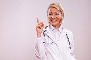 Portrait of mature female doctor  having idea on gray background.