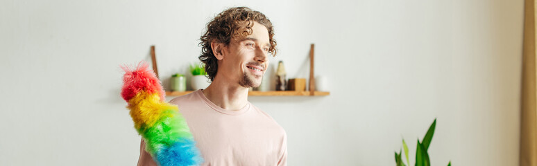A handsome man in cozy homewear holds a multicolored duster.