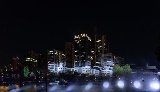 Beleuchtete Skyline einer modernen Metropole bei Nacht mit hell erleuchteten Wolkenkratzern und Spiegelungen auf der Wasseroberfl&auml;che eines Flusses