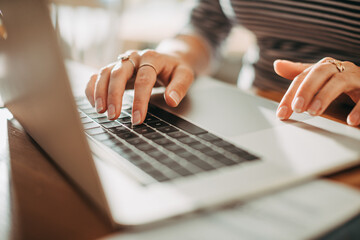 Close-up of woman's hands typing on laptop keyboard