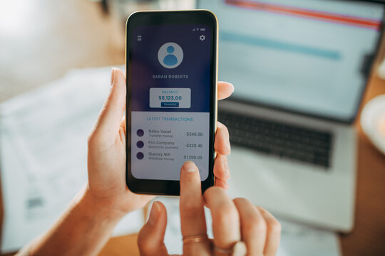 Businesswoman checking financial app on smartphone at office desk