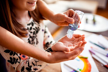 Mother giving daughter hand sanitizer while doing crafts at home