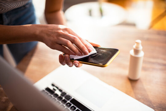 Woman cleaning smartphone screen with disinfecting wipe