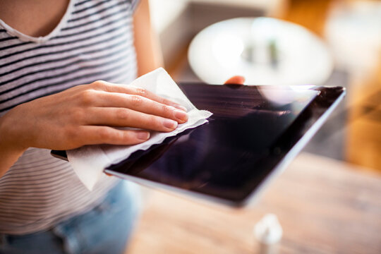 Woman cleaning tablet screen with disinfecting wipe