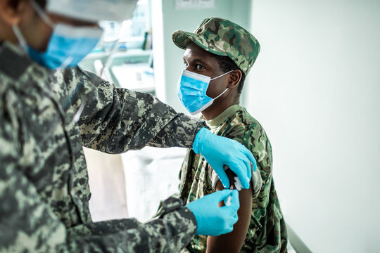 Soldier receiving vaccine from medical personnel in military uniform