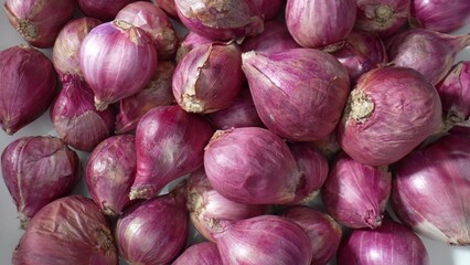 A close-up view captures the intricate textures of red shallots, showcasing their graceful curves...