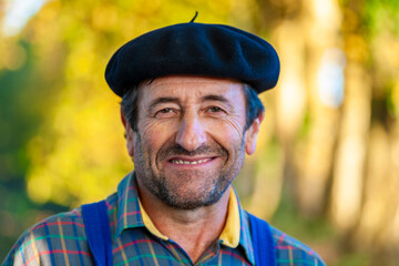 Portrait of a Frenchman, wearing a beret and blue dungarees smiling and gesticulating to camera