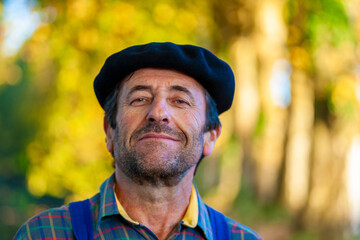 Portrait of a Frenchman, wearing a beret and blue dungarees smiling and gesticulating to camera
