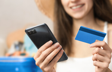 woman holding a smartphone and a bank card in her hands, paying for purchases on the Internet
