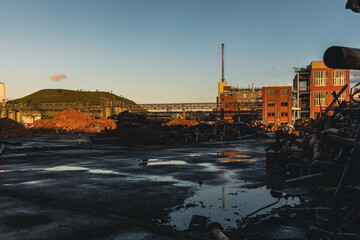 Rückbauzone mit Schrottbergen und Industriehügel im Abendlicht