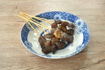 grilled salty beef meat dressings spicy sauce stabbing in wooden stick on plate 