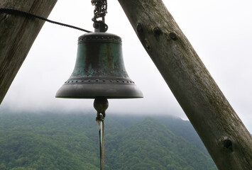 Fototapeta premium Bronze bell hanging with mountainous backdrop