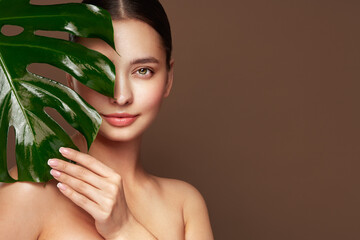 Close up woman face with green exotic leaf. Skin care beauty treatments concept. Model with clean,...