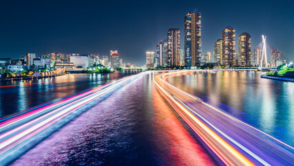 Obraz premium 隅田川を通る船の光跡とタワーマンション群の夜景【東京都・中央区】 City night view of the Sumida River - Tokyo, Japan