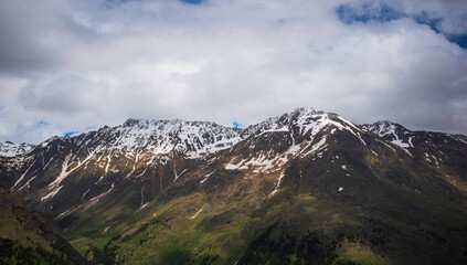 Mountain bright landscape with snow-capped mountain peaks in the distance. Blue sky with fluffy clouds.