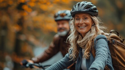 A woman in the foreground smiles brightly while biking with her partner, surrounded by autumn leaves