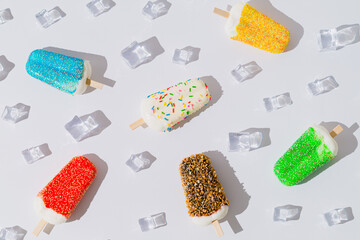 Summer pattern composition made with colorful ice cream popsicles and ice cubes on white background. Minimal creative summer concept. Trendy summertime sweet food layout. Flat lay.