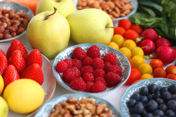 Apples, lemons, bananas, berries, carrots, leek, tomatoes, radishes, spinach and various nuts on white background. Healthy seasonal fruit and vegetable. Selective focus.