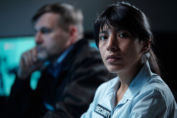 Young confident Hispanic female security guard in uniform looking at camera while sitting by...