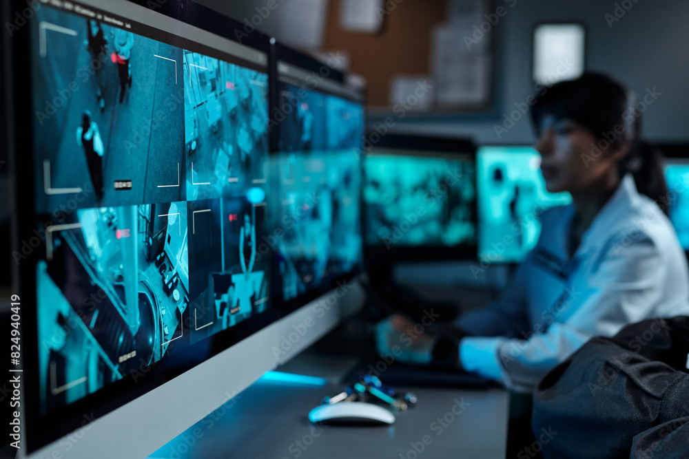 Wall mural Focus on one of several computer screens with cctv video on workplace of modern security guard with female officer on background