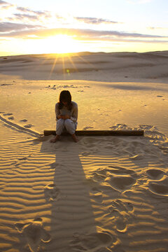 Girl sitting alone at sunset in Birubi beach, Port Stephens, NSW Australia. 