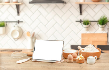 digital tablet and baking ingredients eggs, flour, sugar, butter, yeast, Food recipes, online...