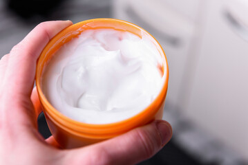 Young woman using body care cream in bathroom.