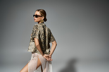 Stylish woman sporting sunglasses and a trendy snakeskin shirt.