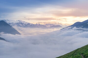 A sea of clouds passes over the valley and between the mountains of the Pyrenees during a sunset....
