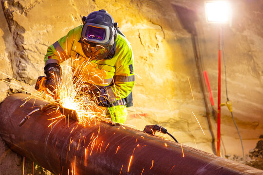 Male electrician uses machinery while cutting pipe in construction industry