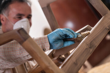 Carpenter applying clear wood stain on furniture