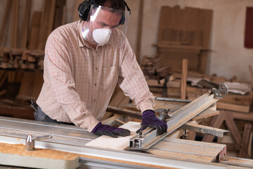 Skilled cabinetmaker using rotary saw, wearing eye and face protection
