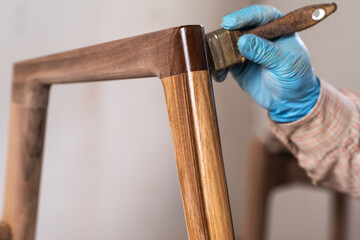 Carpenter applying lacquer to wooden furniture