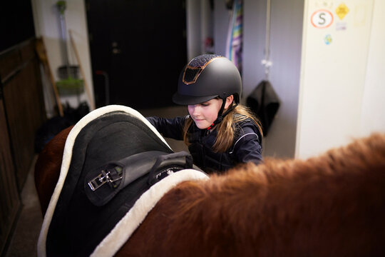 Girl wearing helmet standing with horse