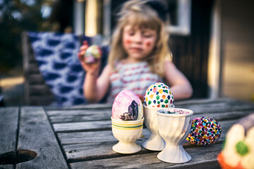 Colorful Easter eggs in containers on table while girl in background