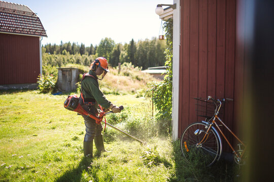 Woman mowing grass in back yard on sunny day