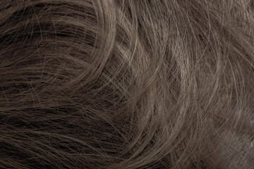 Brown hair close-up as a background. Women's long brown hair. Beautifully styled wavy shiny curls. Hair coloring. Hairdressing procedures, extension.