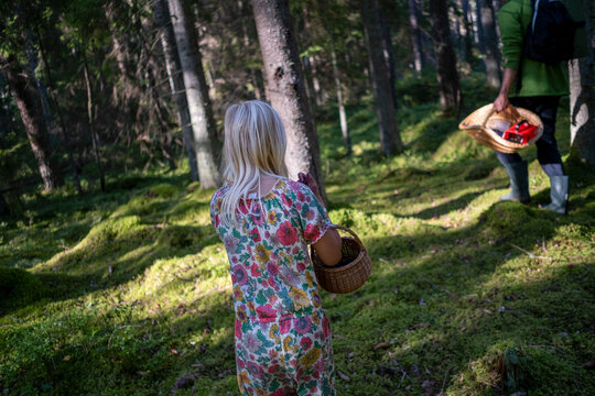Girl wearing printed dress and holding basket while walking in forest