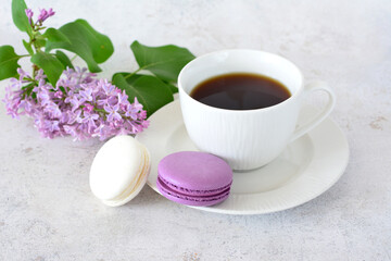 a cup of coffee with purple and white macaroons and lilac branch