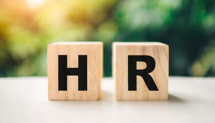 Two wooden blocks with the letters "HR" on a white table symbolize human resources, representing workforce management, recruitment, and employee relations in a professional or corporate setting