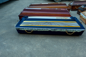 A wooden coffin upholstered in gold and multicolored fabric with a closed lid.