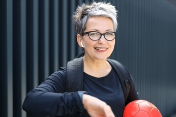 A vibrant mature woman in sportswear with ball.