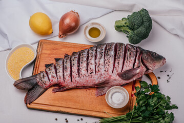 Carp, lemon, broccoli, onion, sea salt, olive oil, parsley. Fresh fish head on a wooden board,...