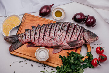 Carp and parsley. Fresh fish head on a wooden board, cleaned, before cooking, onion, sea salt,...