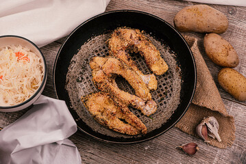 Fried and sliced breaded carp in a pan. Rustic style