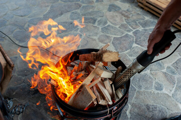 The male hand and warm fireplace with lots of trees ready for barbecue