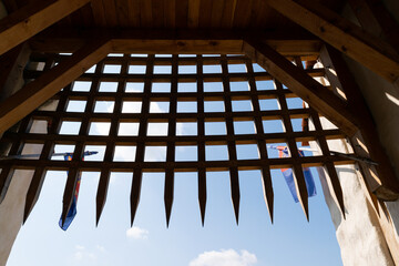 Medieval Wooden Portcullis with Blue Sky and Flags