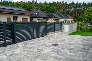 A modern panel fence in anthracite color, visible sliding gate to the garage and a garbage place in...