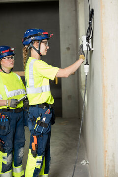 Female engineers working on electrical outlet at construction site
